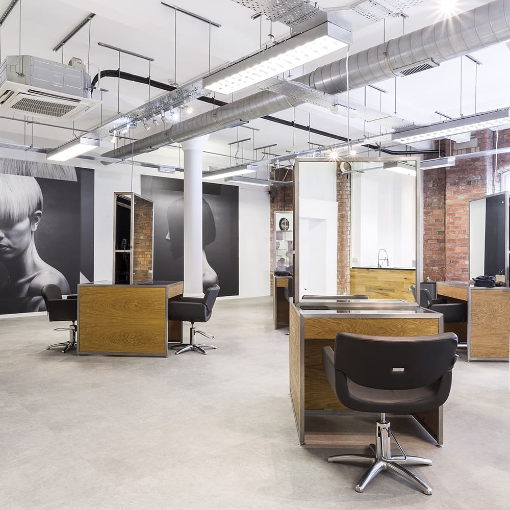 The studio floor — wood-backed stations, black chairs, white columns.
