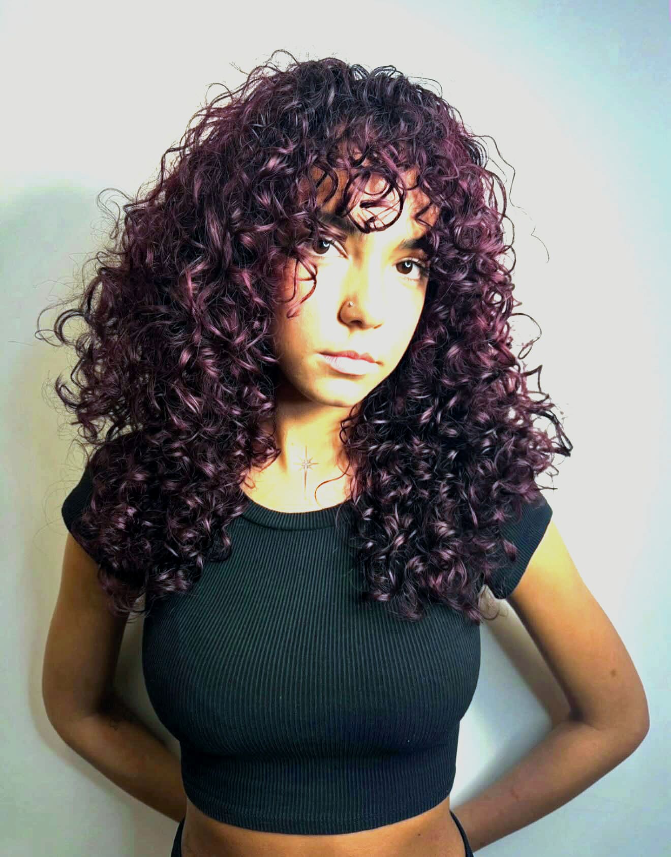 Plum curls with a curtain fringe against a clean white wall.