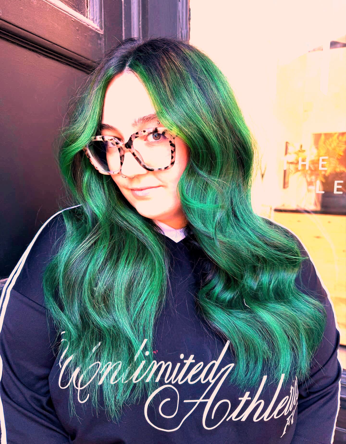 Long emerald-green waves and tortoiseshell glasses, shot at the shopfront.